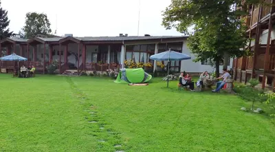 a group of people sitting under umbrellas in a yard at Pripetzite Hotel in Godlevo