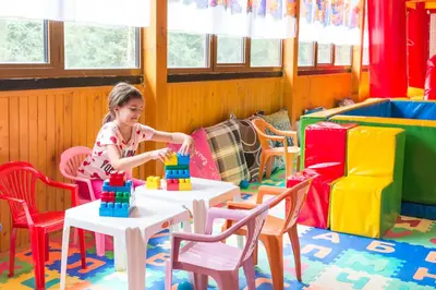 a little girl playing with blocks on tables in a room at Elina Hotel in Pamporovo