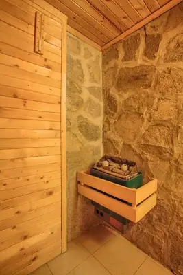 a room with a stone wall and a box of logs at Vezyuva House in Bansko