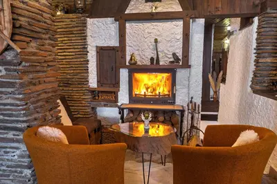 a living room with a fireplace and a table and chairs at Vezyuva House in Bansko