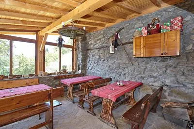 a restaurant with two tables and benches and a stone wall at Guesthouse Vazrozhdenski kashti in Manastir