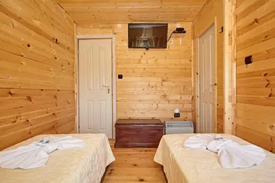 two beds in a room with wooden walls at Guesthouse Vazrozhdenski kashti in Manastir