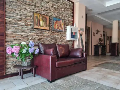 a brown leather couch in a room with a brick wall at Apart Hotel Orbilux in Bansko