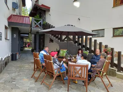 a group of people sitting at a table under an umbrella at Monastery 2 Aparthotel in Pamporovo