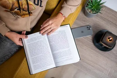 a person sitting on a couch holding a book at Luxor Apartment in Velingrad