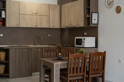 a kitchen with wooden cabinets and a table with chairs at Luxor Apartment in Velingrad