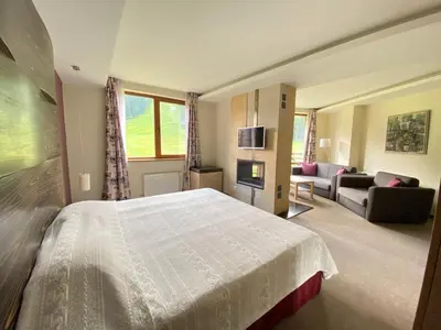 a bedroom with a large bed and a living room at Ice Angels Hotel in Borovets