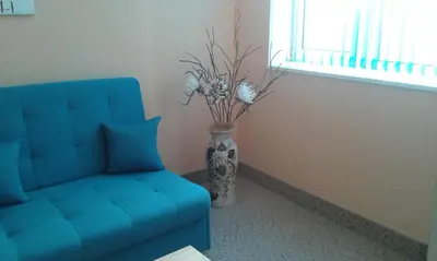 a blue couch and a vase with flowers in a room at Семеен хотел Пауталия in Kyustendil