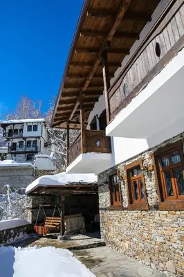 a house in the snow with a wooden roof at Yancheva Guest House in Delchevo