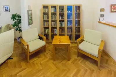 two chairs and a table in a room with a book shelf at Maritza Apartment in Plovdiv