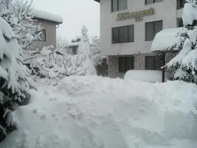 a pile of snow in front of a building at Boutique Guest House IKONOMOV in Bansko
