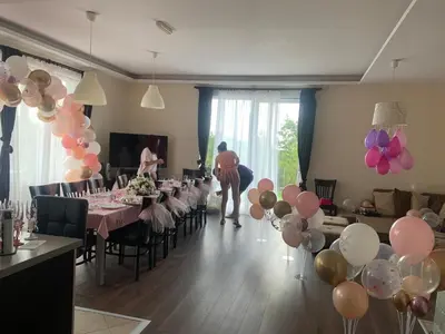 a woman standing in a room with tables with balloons at Vakarel Residence in Vakarel