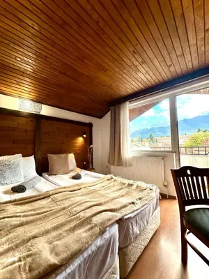 a bedroom with a large bed with a large window at Red House Family house in Bansko