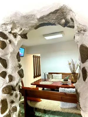 a living room with a table and a stone wall at Red House Family house in Bansko