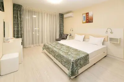 a bedroom with a large white bed and a chair at Hotel Capri in Plovdiv