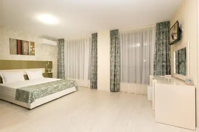 a bedroom with a bed and a large window at Hotel Capri in Plovdiv