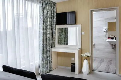 a bedroom with a bed and a mirror and a window at Hotel Capri in Plovdiv