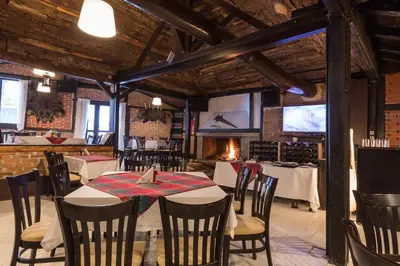 a dining room with tables and chairs and a fireplace at Eco Hotel Zdravetz in Tsar Kaloyan