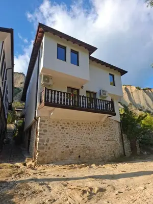 a house with a balcony on top of a stone wall at Apartment R. Dermendzhiev in Melnik