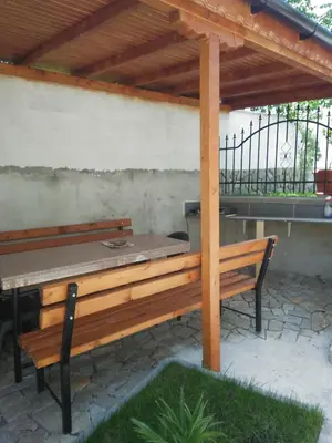 a wooden bench under a pergola with a grill at Guest House Nani in Asenovgrad