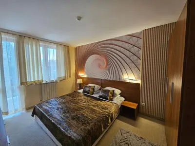 a bedroom with a bed with a painting on the wall at Enjoy Studios and Lovely Apartment Villa Park in Borovets