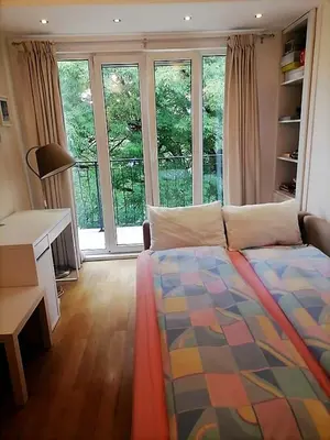 a bedroom with a bed and a desk and windows at Portofino Apartment in Sofia