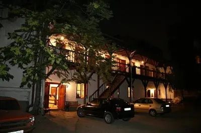 a building with two cars parked in a parking lot at Hostel Mostel Sofia in Sofia