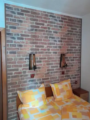 a bedroom with a brick wall and a bed at Mario Complex in Melnik