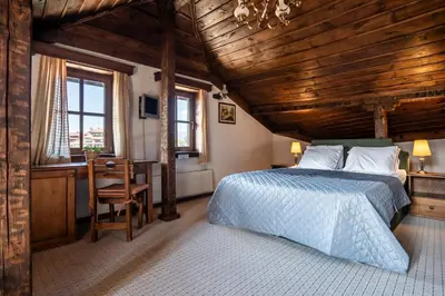 a bedroom with a bed and a desk and windows at Chalet White Fang in Bansko