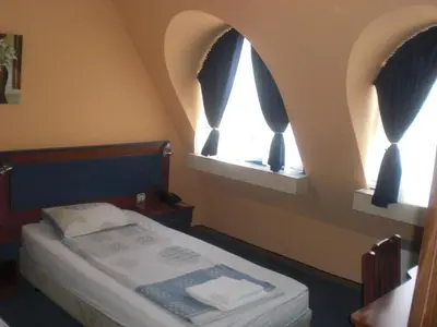 a small bedroom with two windows and a bed at Fenix Family Hotel in Blagoevgrad