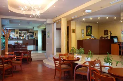 a restaurant with wooden tables and chairs and a bar at Fenix Family Hotel in Blagoevgrad