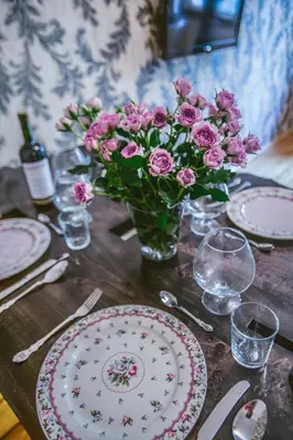 a table with plates and a vase of pink flowers at City Center Stylish 3 Bedroom Apartment in Sofia