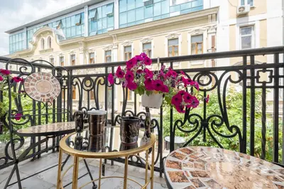 a balcony with tables and chairs and pink flowers at City Center Stylish 3 Bedroom Apartment in Sofia
