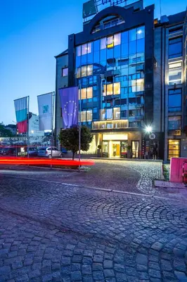 an empty street in front of a building at night at City Avenue Hotel in Sofia