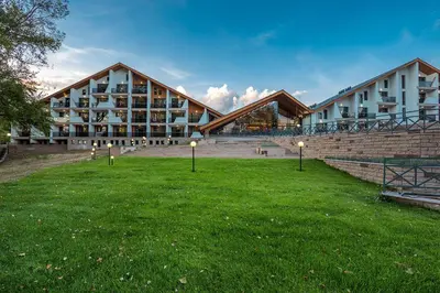 a building with a grass field in front of it at Park Hotel Asarel in Panagyurishte