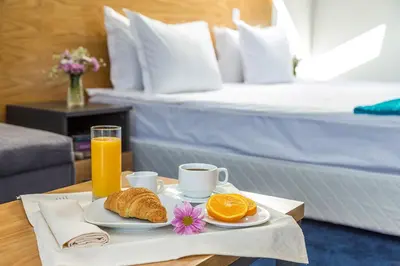a breakfast tray with orange juice and croissants and a bed at Park Hotel Asarel in Panagyurishte