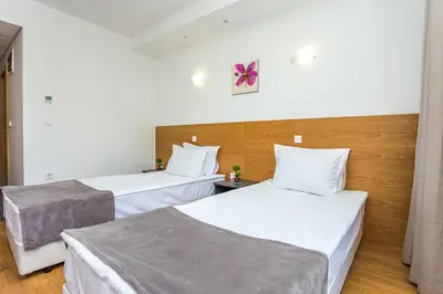 two beds in a hotel room with white sheets at Park Hotel Asarel in Panagyurishte