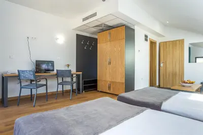 a bedroom with two beds and a desk with chairs at Park Hotel Asarel in Panagyurishte