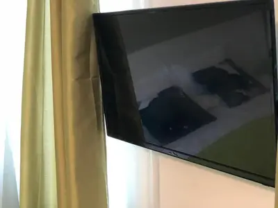 a television hanging on a wall next to a curtain at Terra Guest House in Velingrad