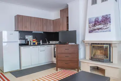 a kitchen with white cabinets and a fireplace at Apartments in Complex Grand Manastira in Pamporovo
