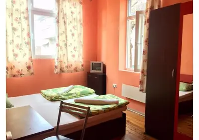 a room with two beds and a table and two windows at Elegance on a Budget - Rooms for Rent in Sofia Center in Sofia