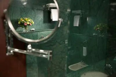 a mirror in a bathroom with a sink and flowers at Grand Hotel Sofia in Sofia