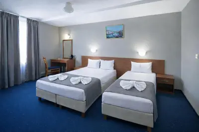 a hotel room with two beds and a desk at Sveta Sofia Hotel in Sofia