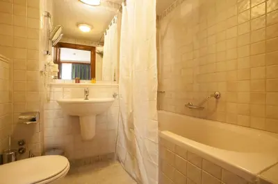a bathroom with a sink and a toilet and a bath tub at Hotel Tanne in Bansko