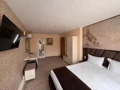a hotel room with a bed and a flat screen tv at Hotel Dafi in Plovdiv