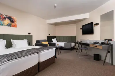 a hotel room with two beds and a desk at Jasmin Hotel in Sofia