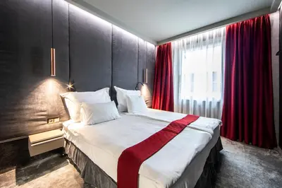 a bedroom with a large bed with red curtains at Spa Hotel Ezeretz Blagoevgrad in Blagoevgrad