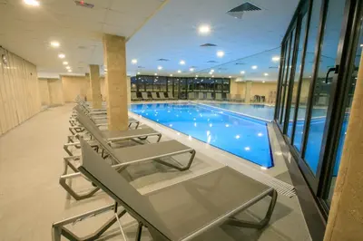 a swimming pool with chairs and a table in a building at Perun Hotel Sandanski in Sandanski