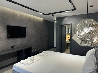 a bedroom with a white bed and a tv at Perun Hotel Sandanski in Sandanski