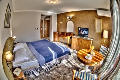 a bedroom with a bed and a table and a television at Meg-Lozenetz Hotel in Sofia